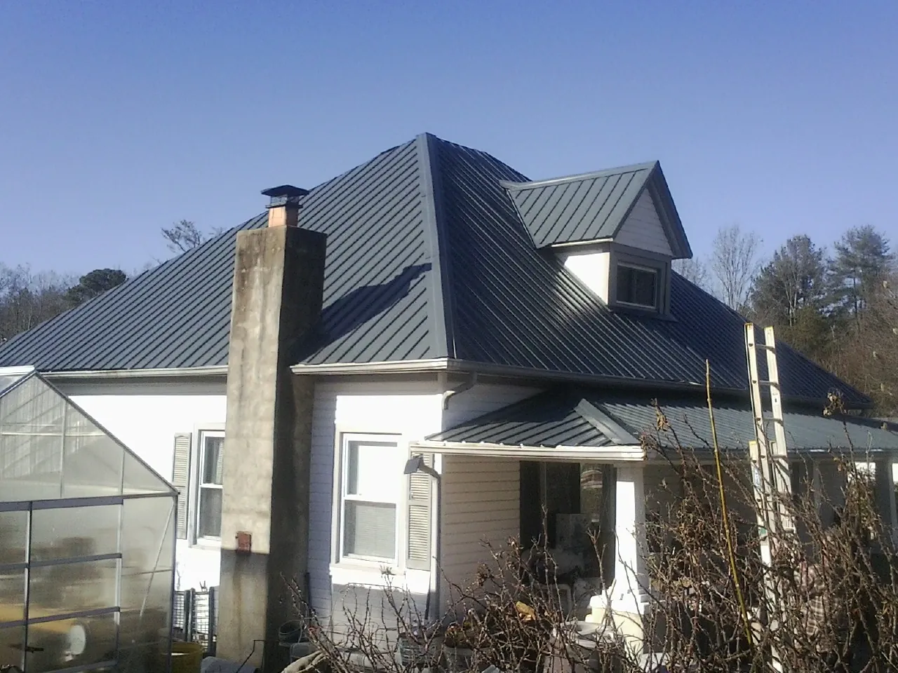 Dark blue standing seam metal roof on a white farmhouse with dormer — Slate & Tile Roof Repair by Roofing Brothers in Fords