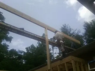 Carpenter setting a ridge beam over a new addition frame — Ice Dam Removal by Roofing Brothers in Fords