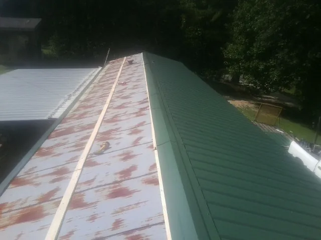 Old rusted panels beside newly installed green metal roofing — Wind Damage Roof Repair by Roofing Brothers in Fords