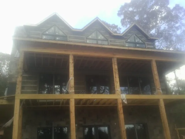 Dormers and porch framing on a large log home under construction — Roof Coating work by our crew in Fords