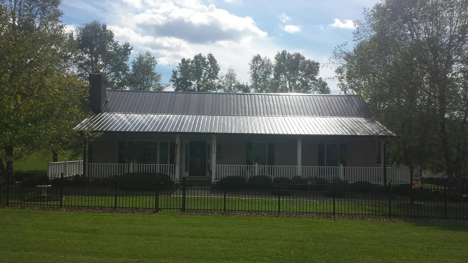Gray metal roof on a brick ranch with a full width front porch — Gutter Guard Installation work by our crew in Fords