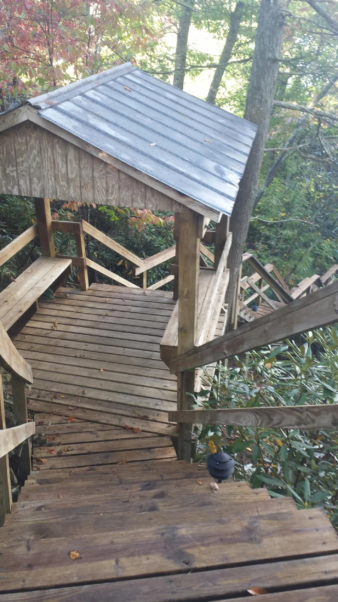 Metal roofed shelter over wooden steps on a wooded walkway — Skylight Repair & Installation work by our crew in Fords