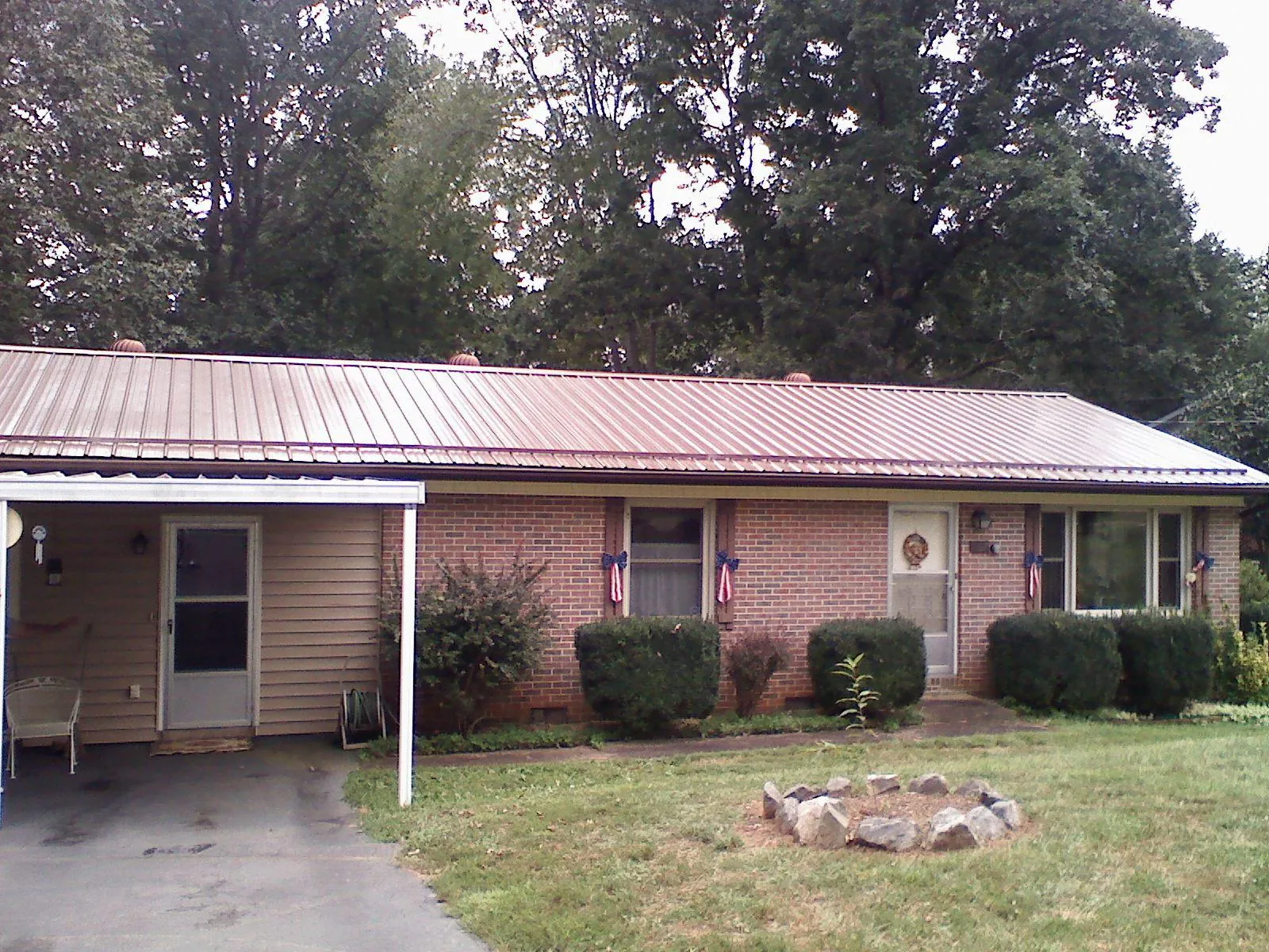 Bronze metal roof and carport on a brick ranch home — Roof Repair work by our crew in Fords