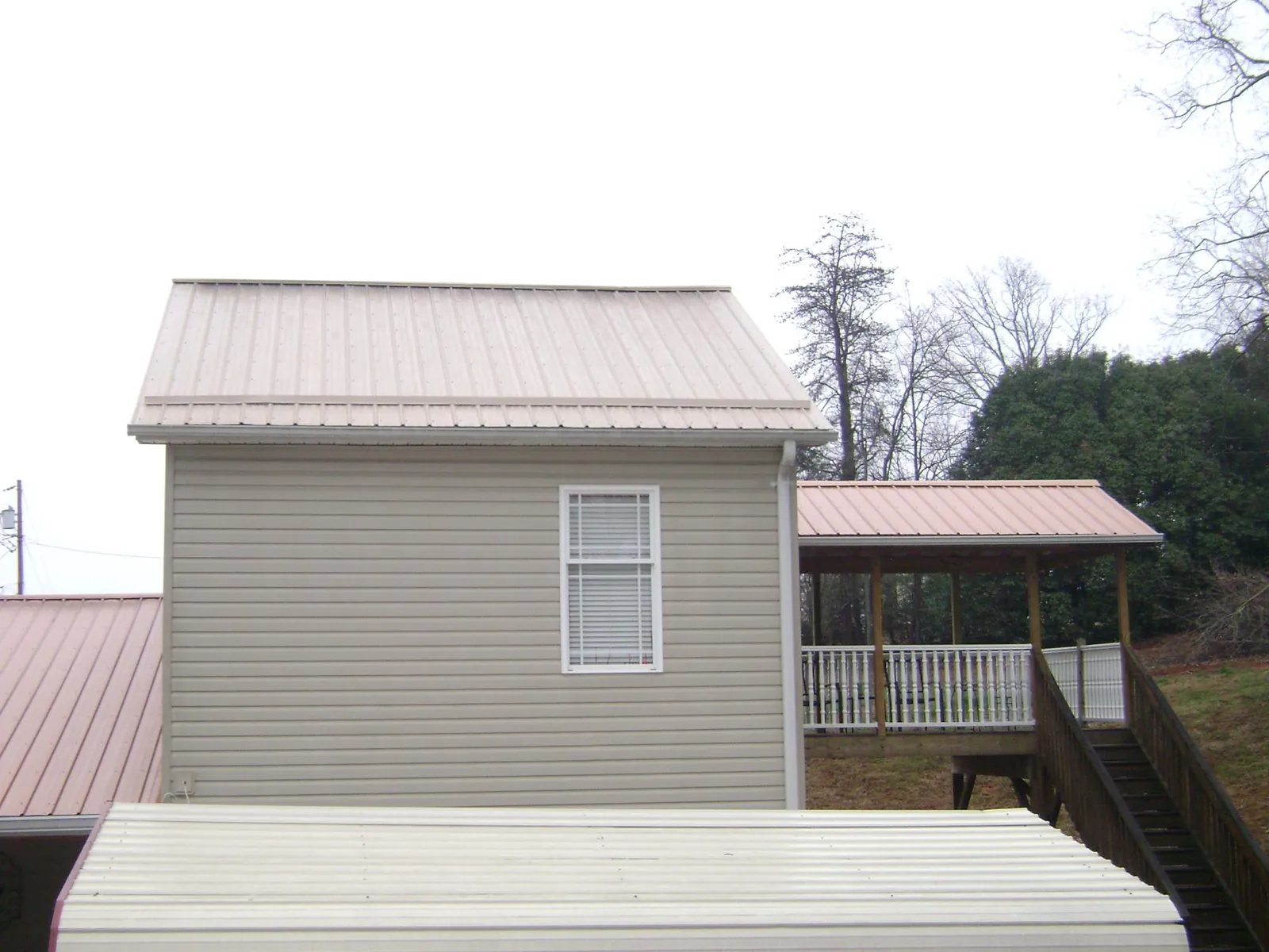Tan metal roofs on a two story addition and attached porch, from a Roof Replacement job in Fords
