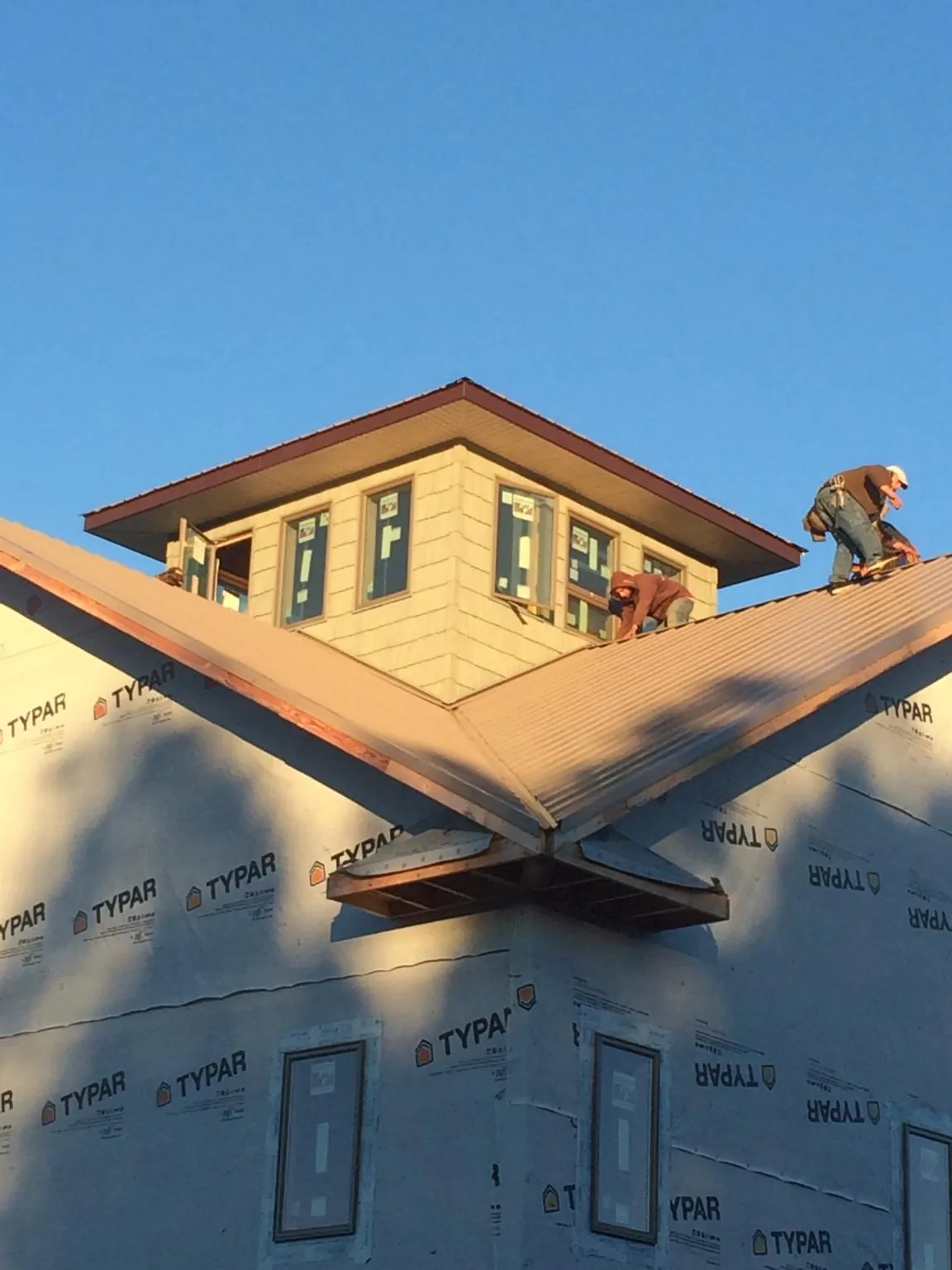 Roofers working around a rooftop cupola on a new metal roof at sunset — Roof Waterproofing in Fords by Roofing Brothers